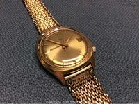 Front view showing gold-tone watch head and mesh bracelet, branded Accutron on dial