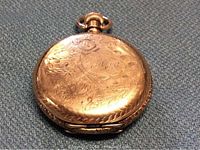 Closed hunter-case pocket watch showing floral engraving on front cover.