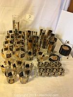 Full set of 1960s glass barware including various glasses, decanter, and coaster set displayed on white cloth.