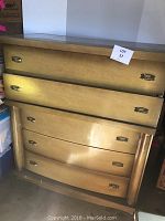 Front view of the chest of drawers showing the five drawers and metal pulls. Loose backing visible.