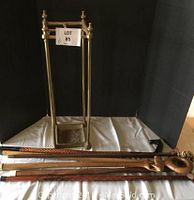 Full set of six decorative wooden canes laid out on a surface against a black backdrop with a brass stand behind.
