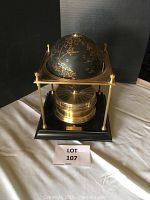 Front view of world clock showing brass globe mounted on black base