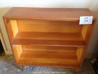 Front view of the wooden bookshelf showing two horizontal shelves and the wear on surface.