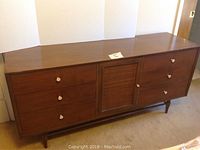 Front view of walnut-finish dresser showing six external drawers and central rattan door