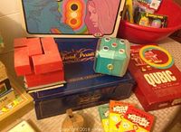 Photo of stacked board games including Concentration, Battleship, Stratego, The Pink Panther, Othello, Trivial Pursuit, Qubic, with puzzle blocks and small toy items on display