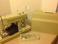 Full view of Sears Kenmore sewing machine with foot pedal, accessories container, and hard carrying case beside it on table.