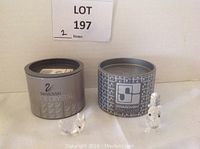 Two Swarovski lead crystal figurines, a bunny and a squirrel, placed beside their original branded round metal boxes.