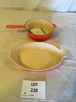 Both orange-colored cookware pieces showing sauce pan inside oval baking dish with lot number card