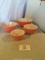 Set of four Pink Flamingo Pyrex mixing bowls displayed together on fabric surface.