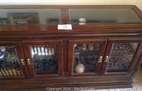 Front view of the Asian wood buffet showing four glass-paneled doors with visible interior shelving and decorative contents inside.