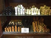 Top shelf showing three distinct chess piece sets including black onyx, white onyx, and light brown carved set