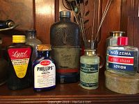 Photo of 6 vintage bottles including Lysol Disinfectant Antiseptic, Phillips Tablets, green Antiseptic Surgical Powder, Noxzema After Shave Lotion, and two more bottles of varying colors and sizes