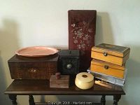 Walnut two-tier magazine table with assorted boxes on top and grouped items in front