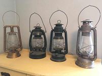 Group shot of four metal oil lanterns in various finishes