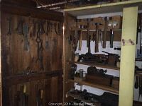Wooden shelving unit with various wrenches and spanner-style tools hanging on backboard