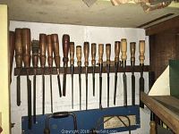 Rack of wood–handled chisels hung on wall