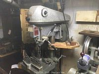 Full view of drill press with drill bits tray and surrounding workspace