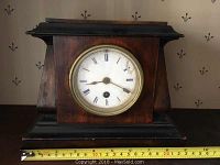 Front view of the French petit mantel clock showing wooden body, brass bezel, and tape measure for size approximation.