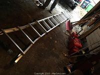 Extended aluminum articulating ladder laid on garage floor