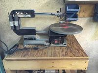 Scroll saw positioned on homemade wooden table with caster wheels