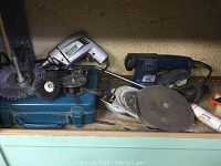 Shelf view showing two drills, sander, wire brushes and discs.