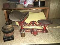Antique cast iron two-pan balance scale with decorative red and gold paint and original removable pans