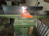 Front view showing infeed and outfeed tables, adjustable fence, and orange push block