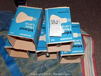 Five Sylvania infrared heat lamp bulbs in original blue boxes, stacked together showing tops open revealing bulbs.