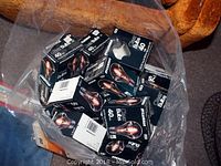 Bag containing multiple 40 watt black packaged Sylvania incandescent bulbs on an orange chair.