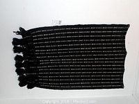 Full view of black handwoven cotton shawl with white vertical ikat stripes and tasseled ends.