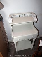 Front and side view of painted wood side table showing gallery top, pull-out drawer, and lower shelf