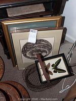 Framed prints leaning against wall with wire basket in front
