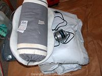 Top view of queen size Aerobed air mattress partially folded with feather pillow and black Aerobed electric air pump on top