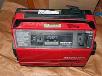 Front view of generator controls showing circuit protector switch, AC outlet label area and Honda logo on housing