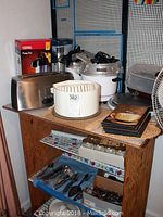 Photo showing a white rice cooker steamer, large Breville toaster, red Thermos pump pot dispenser, Trudeau insulated carafe, glass jelly jars, coffee percolator, plates on wooden cabinet