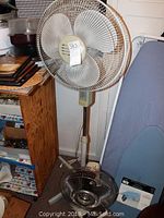 Wind Chaser 3-speed floor fan standing on the floor next to wooden cabinet and ironing board