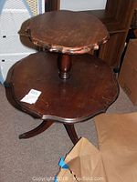 Angle view of top tier and claw foot base showing wear and scalloped edges