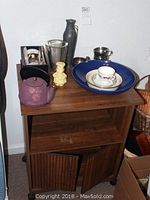 Wooden cabinet with various decorative items on top including tea set, bowls, vases, and figurines.