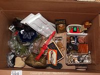 Wide view of box containing various costume jewelry, watches, key chains, metal purse, and other accessories.