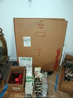 Wide view of the lot showing two cardboard easel pads behind boxes containing various office supplies and reflectors.