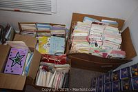 Four large boxes filled with assorted greeting cards, cards are standing upright organized by category or occasion.