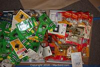 Photo showing a collection of electrical parts such as toggle switches, clips, outlets, and mini breakers, all unopened and in their original packaging.