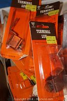 Photo of multiple unopened orange and black packages of terminal lugs marked Holub, with yellow price stickers