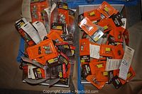 Box containing numerous unopened electrical supplies including clips and connectors in original packaging.