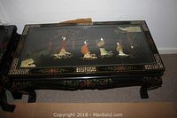 Top-down photo showing the entire rectangular black lacquer coffee table with Chinoiserie painted and gilt decorations and mother of pearl inlays of figures and nature scenes.