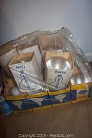 Multiple boxes of new reflector flood lamp bulbs, blue and yellow GE branded packaging with bulbs inside boxes, plastic wrapped bag.