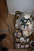 Box filled with multiple packs of mostly flame decorative light bulbs in packaging along with a plastic bag containing other loose bulbs.