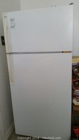 Front view of white two door Kenmore refrigerator with upper freezer showing exterior condition.