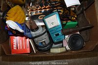 Box showing assorted tools including a blue Dwell Meter and Tachometer, an electric drill, and other hand tools.