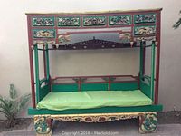 Full front view of bed showing canopy frame, cushion and carved base
